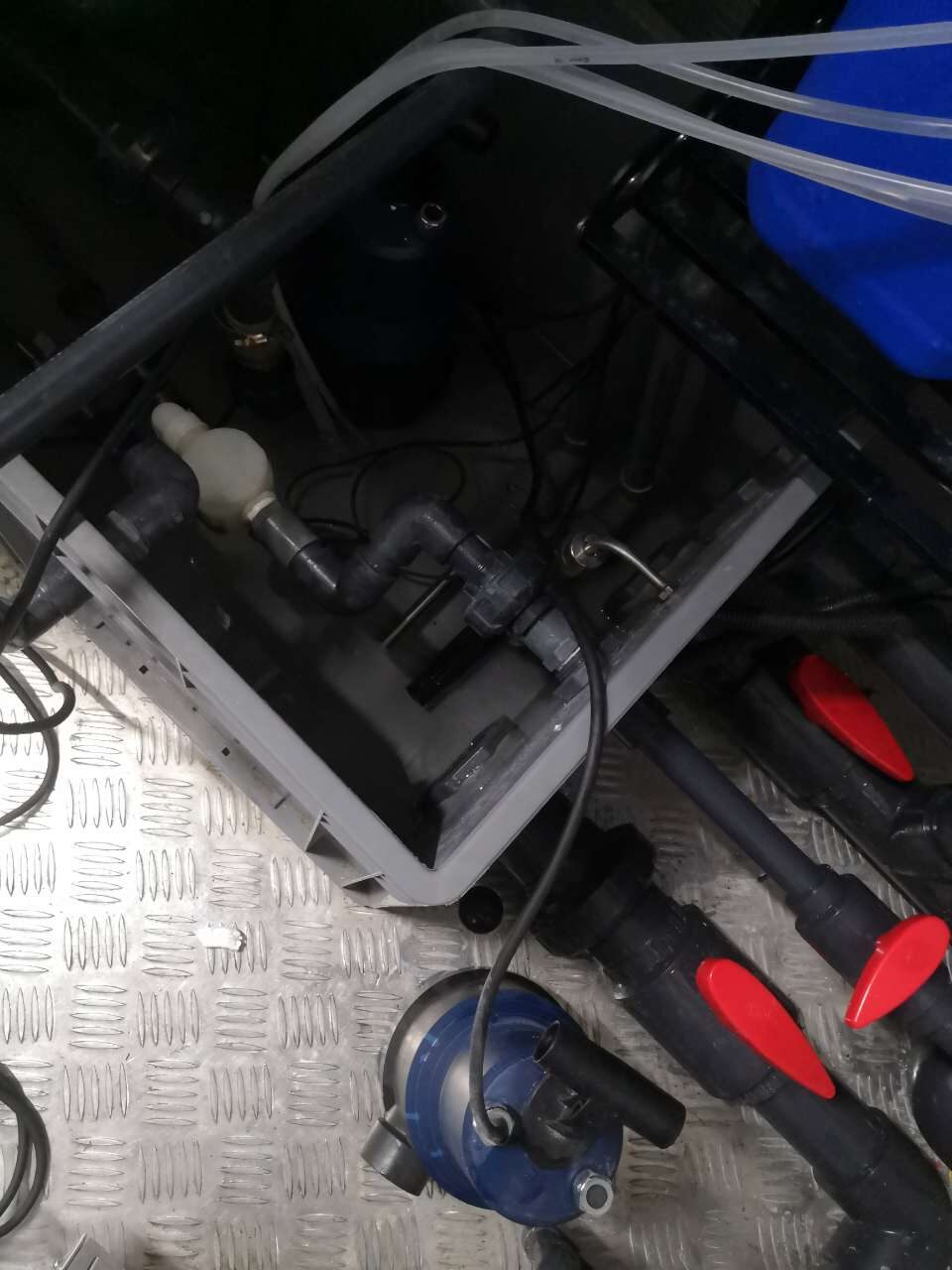 Open sump with pump and manifold, red isolation valves on the diamond-plate floor
